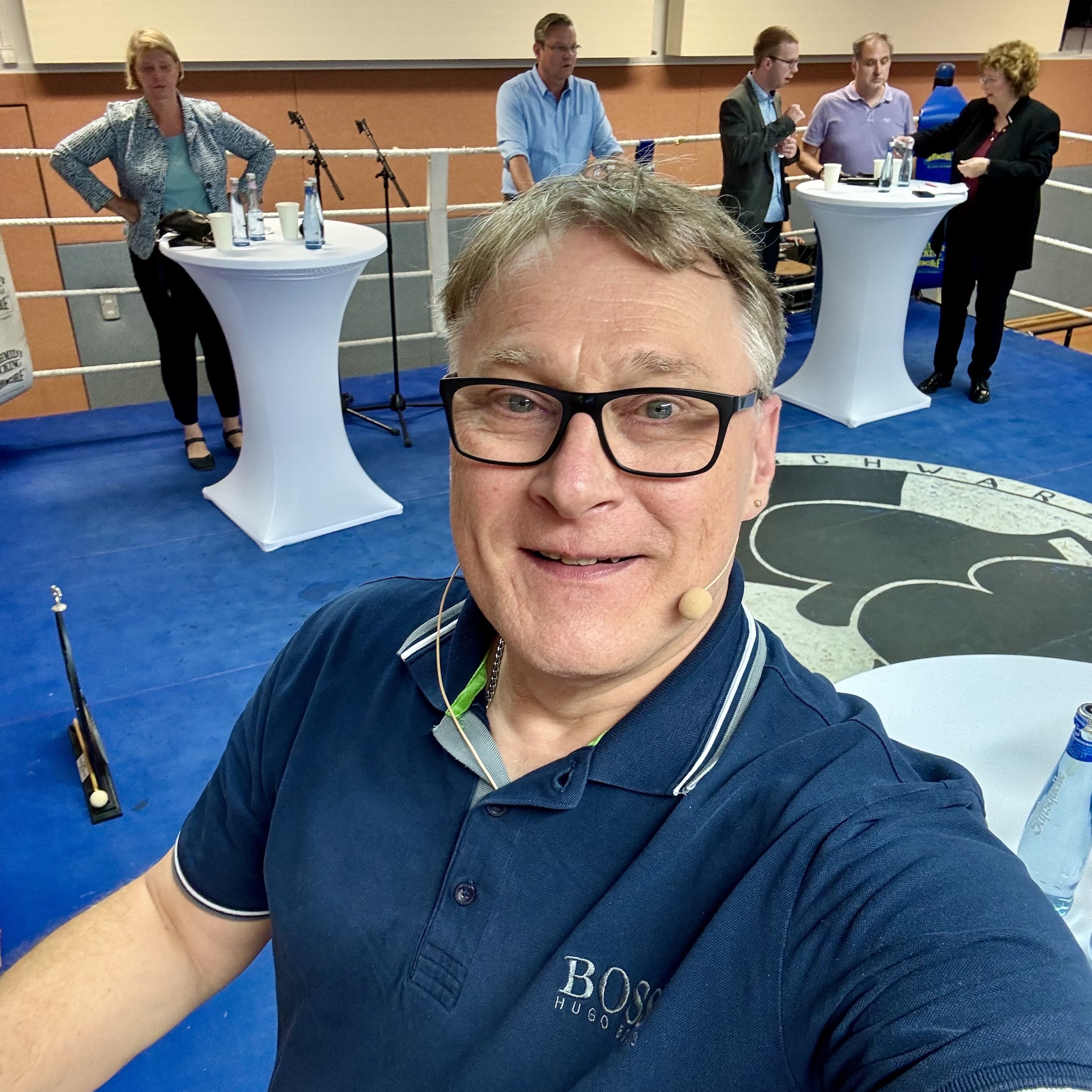 Achim Preikschat steht mit Politikerinnen und Politikern für eine Podiumsdiskussion im Ring eines Boxvereins. | Foto: Achim Preikschat